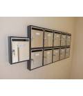 Agrupaciones de 11 buzones Teide, de color Inox Brillo. Colgados en la pared.